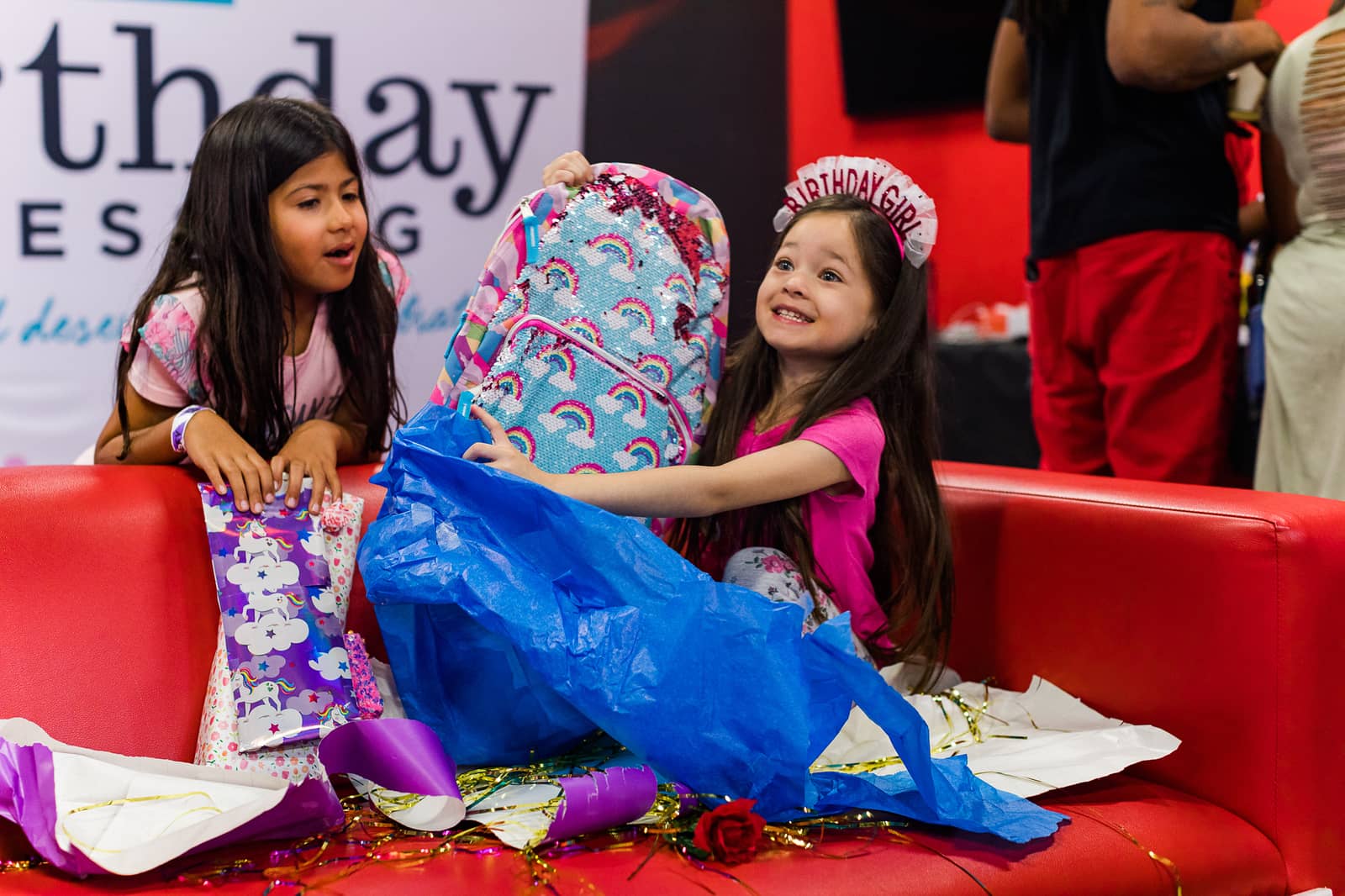 Birthday Girl smiling with joy as she opens up her presents at Birthday Blessing Event